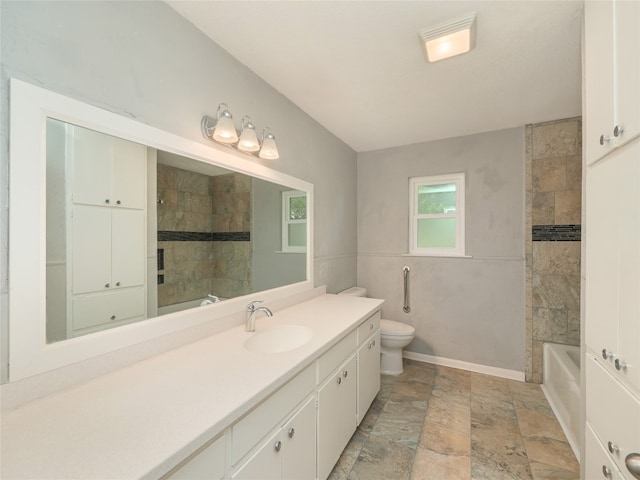 bathroom featuring toilet, vanity, and stone tile floors