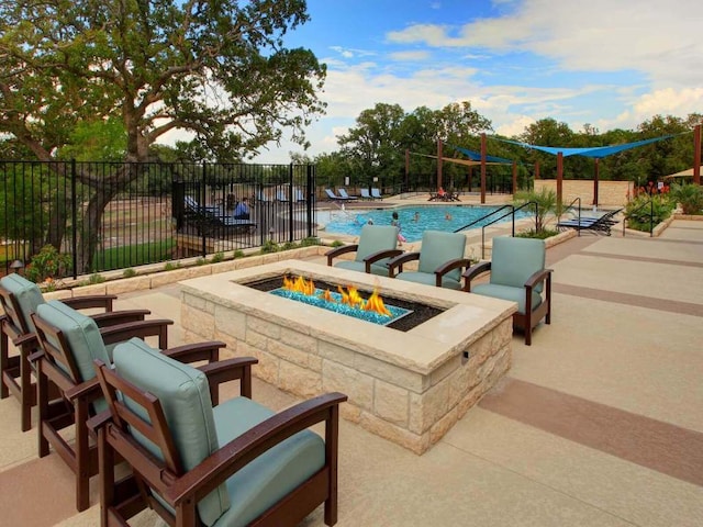 community pool with an outdoor fire pit, a patio area, and fence