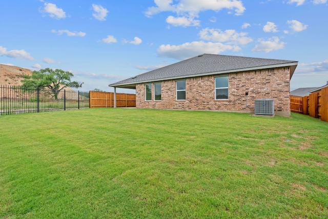 409 Rivers Edge Dr, Georgetown, TX 78628 - back of house featuring roof with shingles, brick siding, central AC, a yard, and a fenced backyard