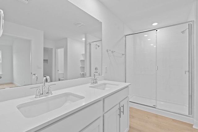 409 Rivers Edge Dr, Georgetown, TX 78628 - full bathroom featuring double vanity, wood finished floors, a shower stall, and a sink
