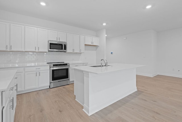 409 Rivers Edge Dr, Georgetown, TX 78628 - kitchen with a sink, white cabinetry, decorative backsplash, light wood-style floors, and appliances with stainless steel finishes