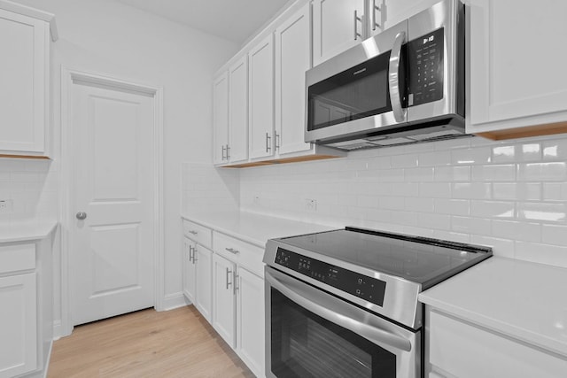 409 Rivers Edge Dr, Georgetown, TX 78628 - kitchen featuring light wood-style flooring, white cabinetry, backsplash, light countertops, and appliances with stainless steel finishes