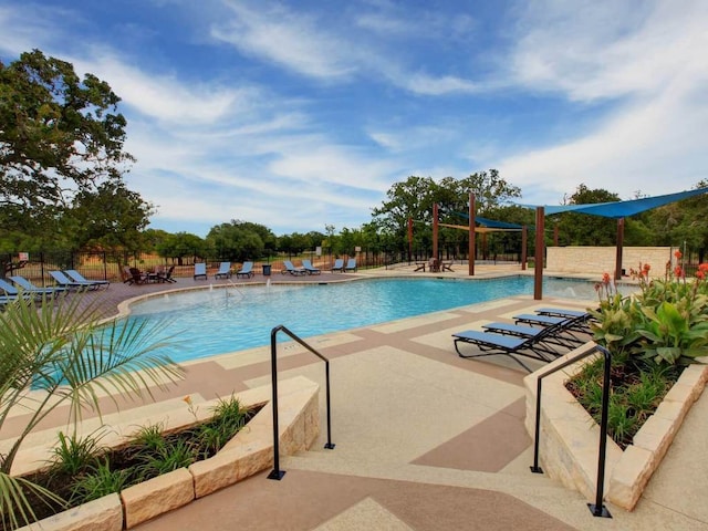 community pool with a patio area and fence