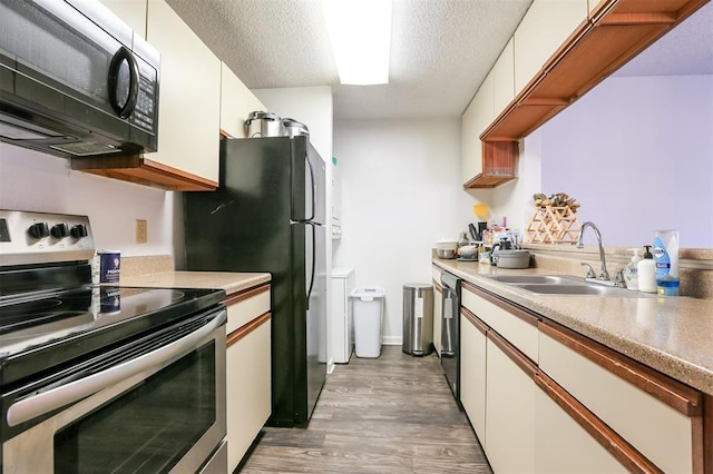 912 W 22nd St Unit 307, Austin, TX 78705 - kitchen featuring appliances with stainless steel finishes, a sink, light wood finished floors, white cabinetry, and a textured ceiling