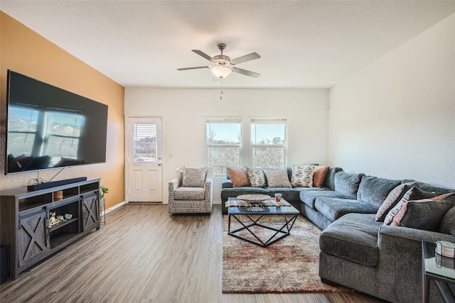 living area featuring baseboards, wood finished floors, and a ceiling fan