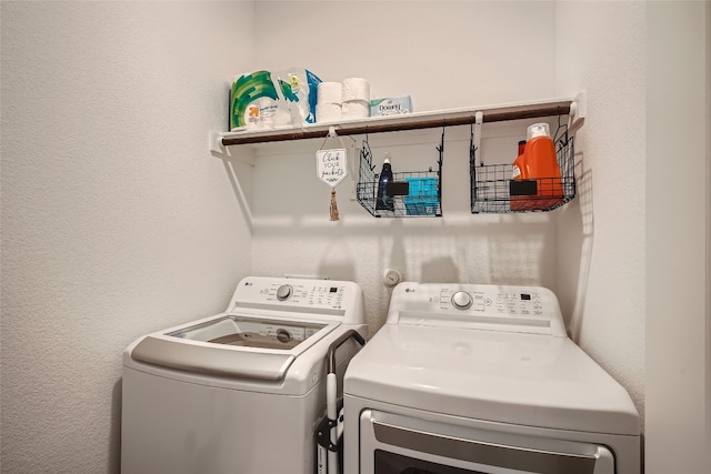 clothes washing area with washing machine and dryer, laundry area, and a textured wall
