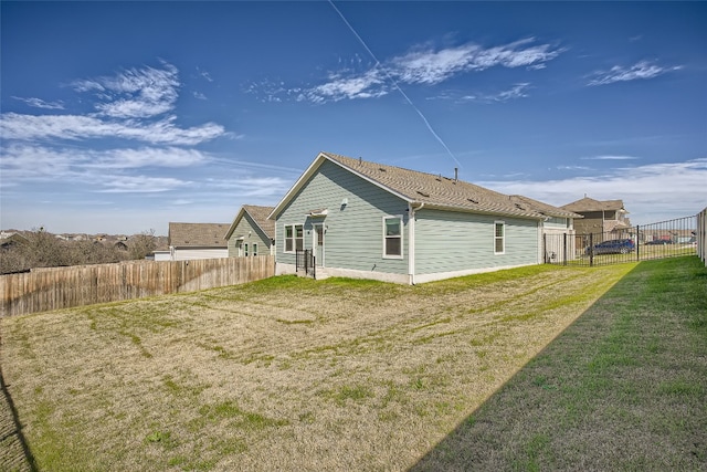 rear view of house featuring a yard and a fenced backyard