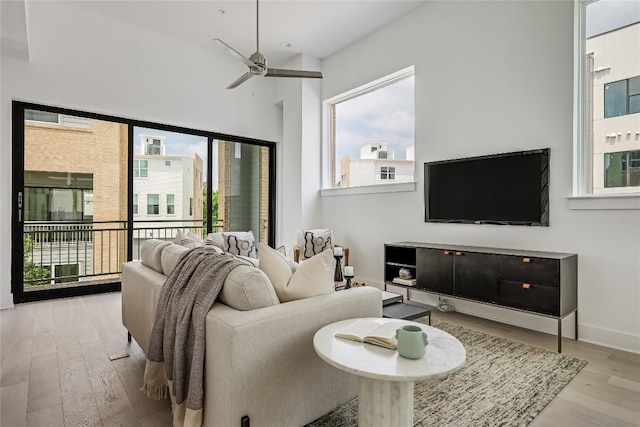 living room featuring baseboards, wood finished floors, and a ceiling fan