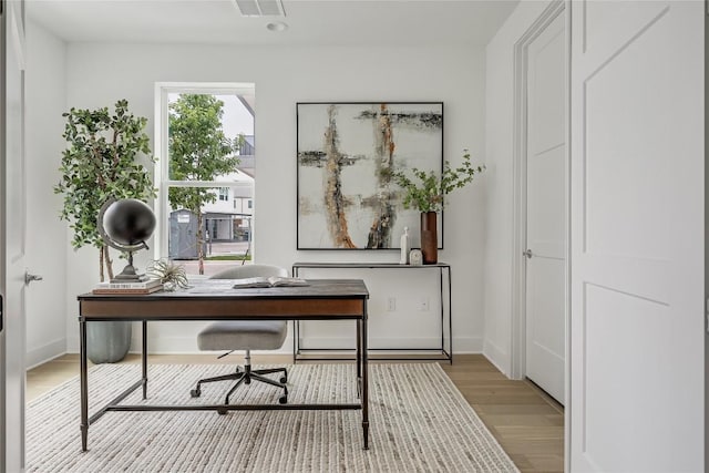 home office with baseboards and wood finished floors