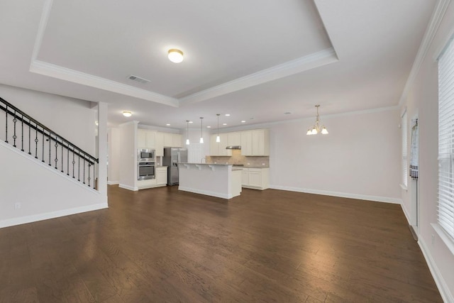 unfurnished living room featuring a raised ceiling, an inviting chandelier, visible vents, and dark wood-type flooring