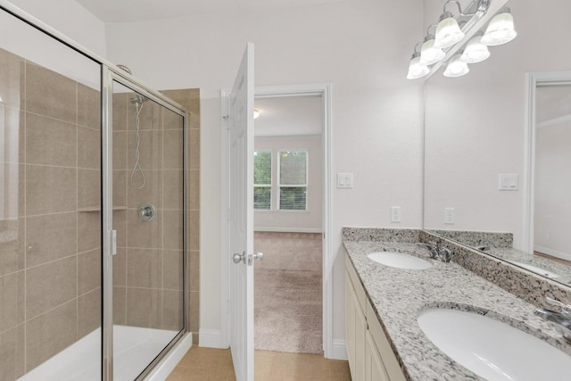 full bath with a stall shower, a notable chandelier, double vanity, and a sink