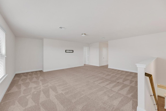 spare room with visible vents, baseboards, and light carpet
