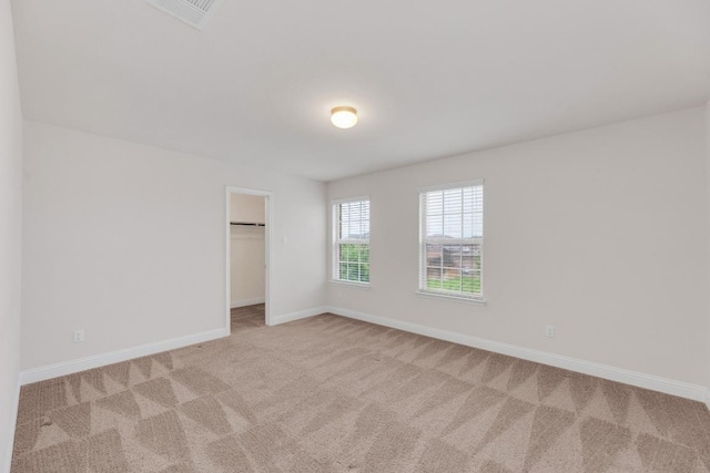 unfurnished bedroom with a closet, visible vents, carpet floors, a walk in closet, and baseboards