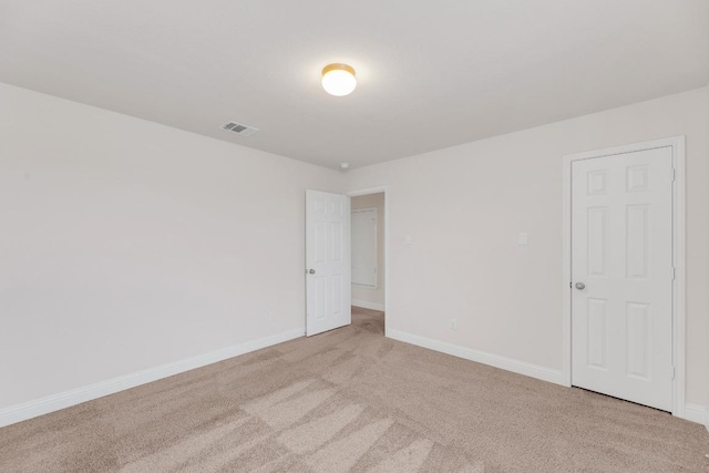 empty room with carpet, visible vents, and baseboards