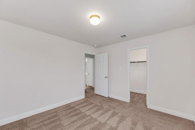 unfurnished bedroom with carpet floors, baseboards, a spacious closet, and a closet