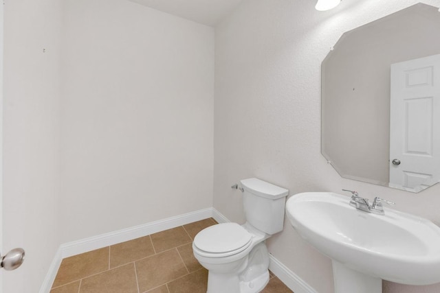 bathroom with toilet, tile patterned flooring, baseboards, and a sink