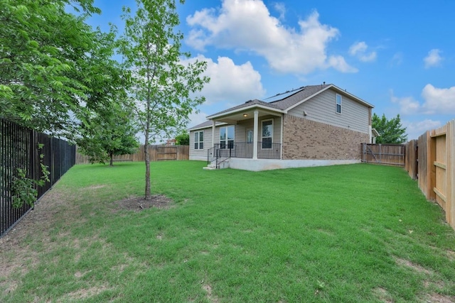 rear view of property featuring a fenced backyard, brick siding, and a lawn