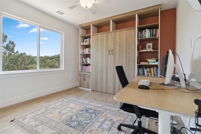office space with baseboards, ceiling fan, light wood-type flooring, and visible vents