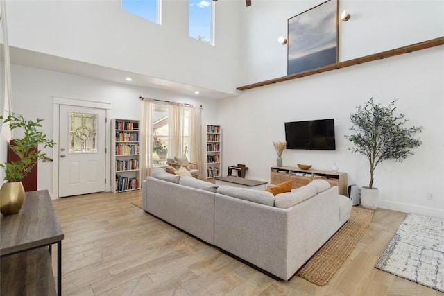 living area with light wood-style flooring and a towering ceiling