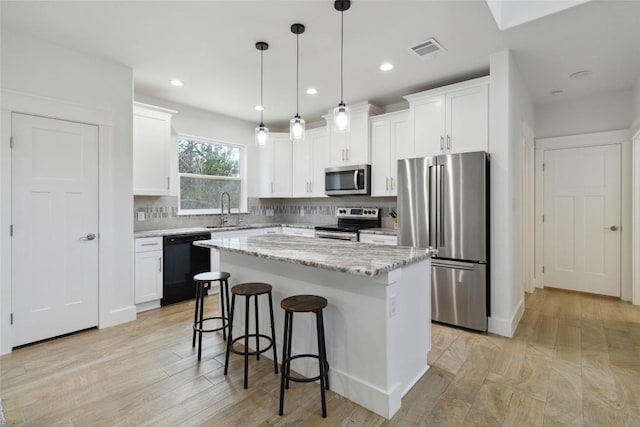 kitchen featuring a sink, stainless steel appliances, a kitchen breakfast bar, visible vents, and decorative backsplash