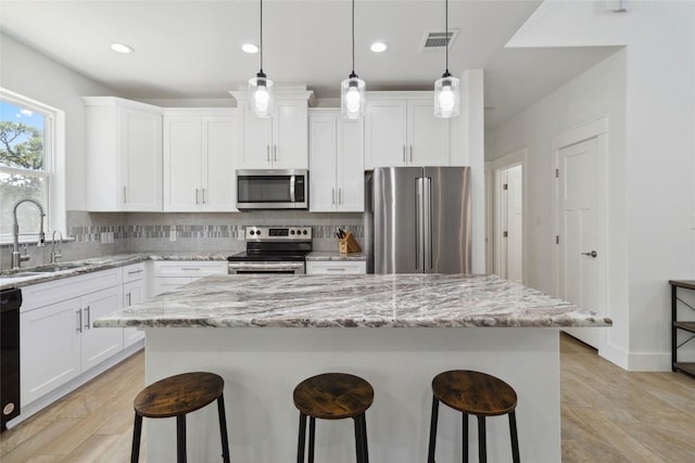kitchen with a center island, a breakfast bar area, stainless steel appliances, and a sink
