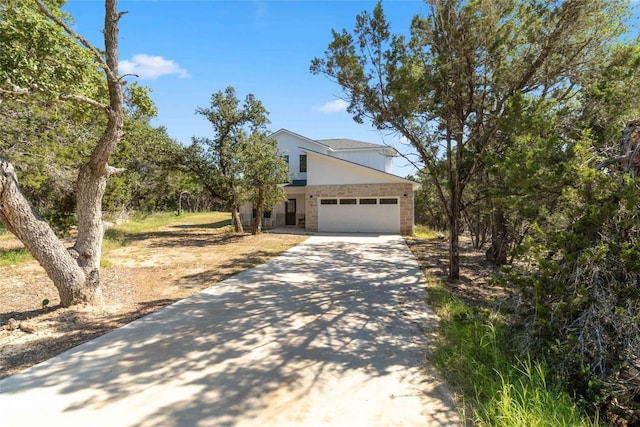 view of front of house with an attached garage, brick siding, and driveway