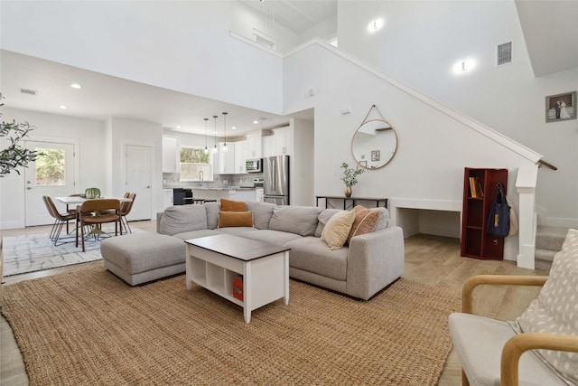 living area with stairs, a wealth of natural light, visible vents, and recessed lighting