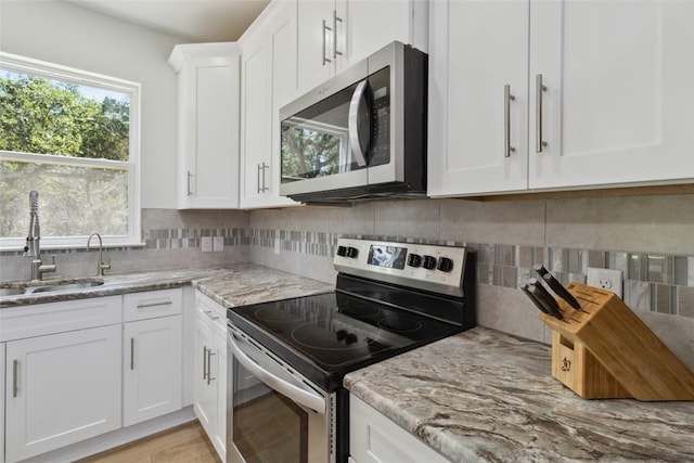 kitchen with a healthy amount of sunlight, white cabinets, appliances with stainless steel finishes, and a sink