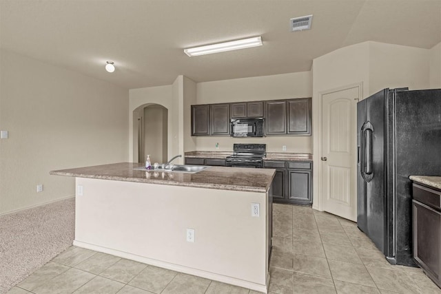 1021 Polmont Ct, Seguin, TX 78155 - kitchen with a sink, dark brown cabinetry, a center island with sink, arched walkways, and black appliances