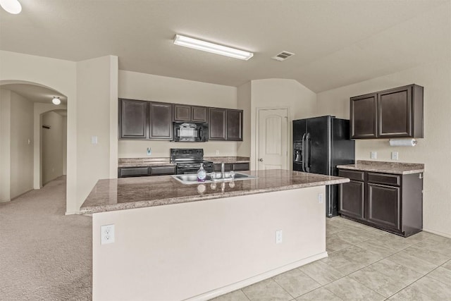 1021 Polmont Ct, Seguin, TX 78155 - kitchen featuring black appliances, arched walkways, dark brown cabinetry, an island with sink, and stone counters