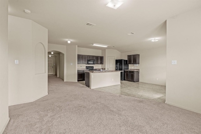 1021 Polmont Ct, Seguin, TX 78155 - kitchen with light colored carpet, black appliances, open floor plan, arched walkways, and a kitchen island
