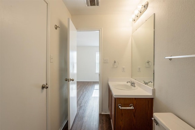 bathroom with toilet, vanity, visible vents, and wood finished floors