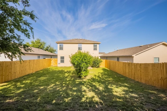 rear view of house with a fenced backyard, stucco siding, and a yard