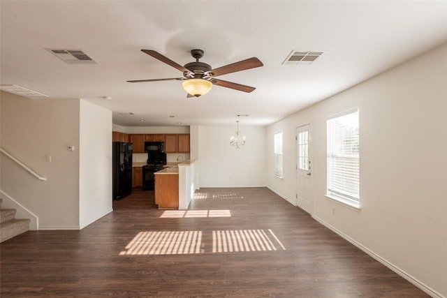 unfurnished living room with baseboards, stairway, visible vents, and ceiling fan with notable chandelier