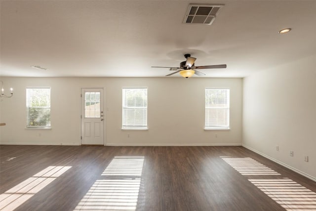 unfurnished room with baseboards, visible vents, dark wood-style floors, and ceiling fan with notable chandelier