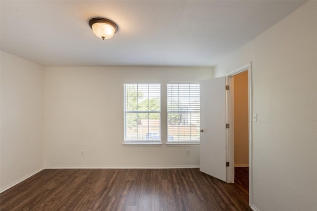 unfurnished room featuring baseboards and dark wood-style floors