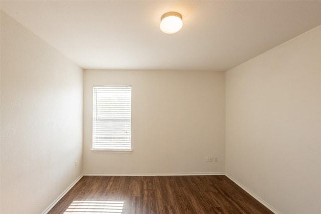empty room with baseboards and dark wood-type flooring