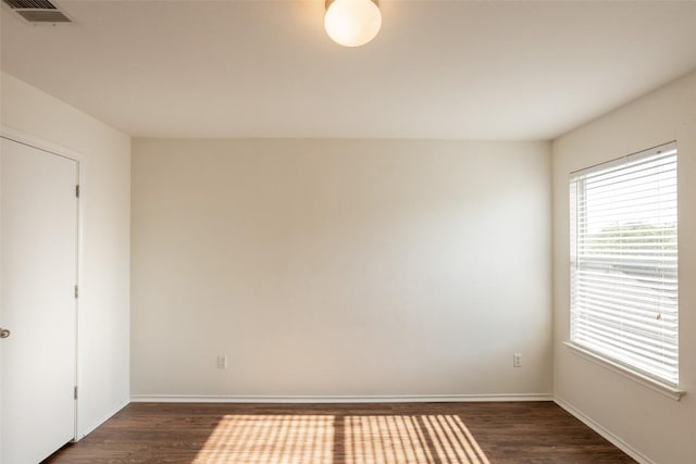 unfurnished room with dark wood-style flooring, baseboards, and visible vents