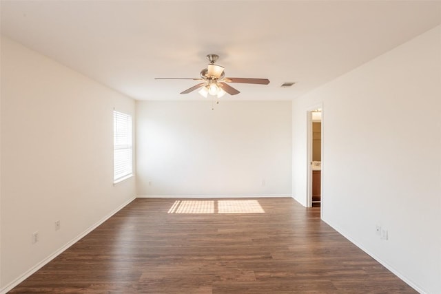 spare room with baseboards, dark wood-style flooring, visible vents, and ceiling fan