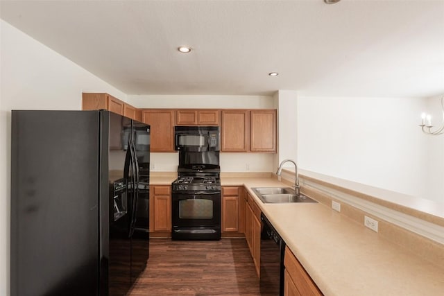 kitchen with a sink, a notable chandelier, dark wood-type flooring, black appliances, and light countertops