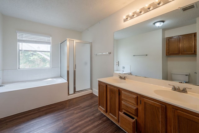 1304 Green Terrace Dr, Round Rock, TX 78664 - full bathroom with wood finished floors, toilet, a garden tub, a stall shower, and a textured ceiling
