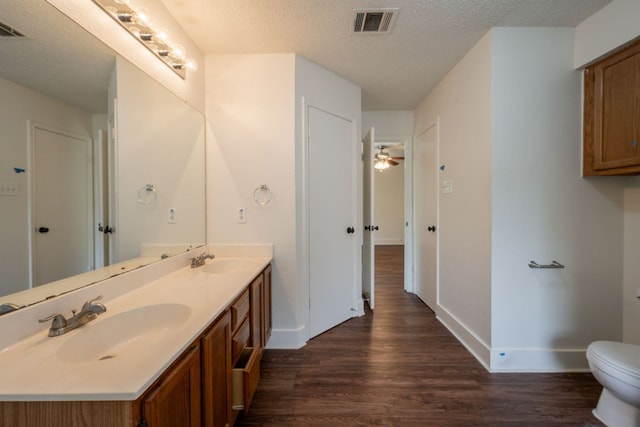 1304 Green Terrace Dr, Round Rock, TX 78664 - bathroom with wood finished floors, double vanity, toilet, a textured ceiling, and baseboards