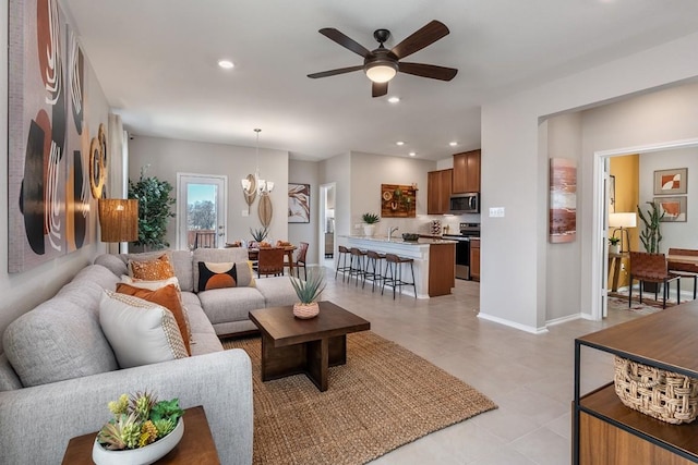 living room with baseboards, ceiling fan with notable chandelier, and recessed lighting