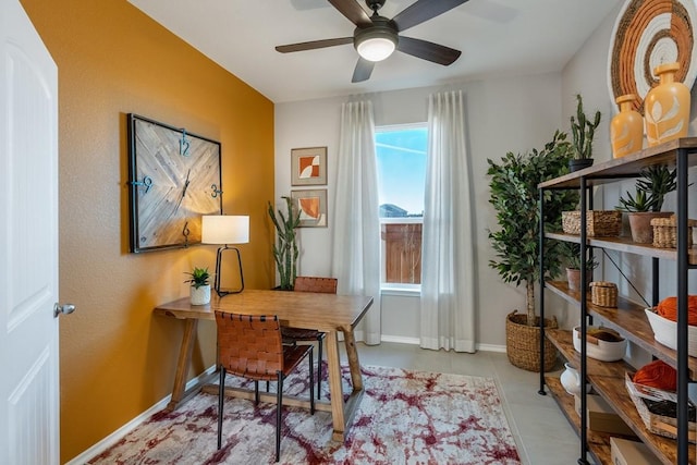 office space with a ceiling fan and baseboards
