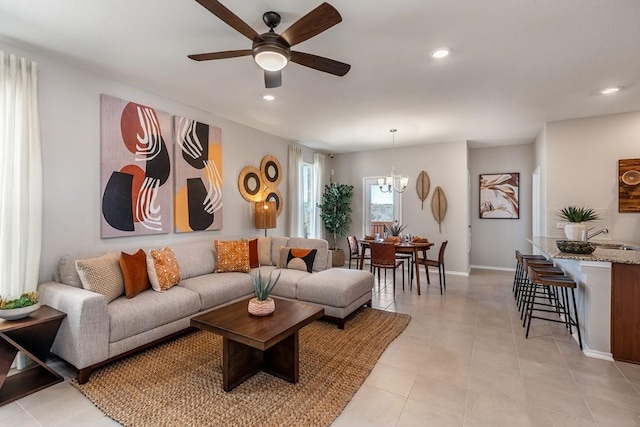 living room with baseboards, ceiling fan with notable chandelier, and recessed lighting