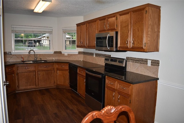 1007 N Bishop St, San Marcos, TX 78666 - kitchen featuring stainless steel appliances, a sink, brown cabinetry, dark countertops, and a textured ceiling