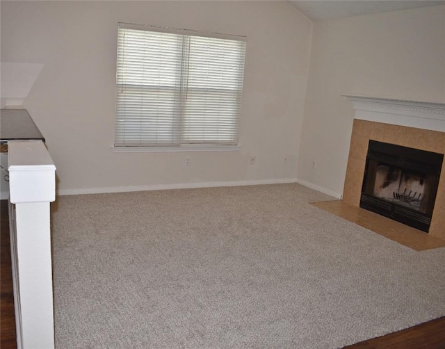 1007 N Bishop St, San Marcos, TX 78666 - unfurnished living room featuring a tiled fireplace, carpet floors, and baseboards