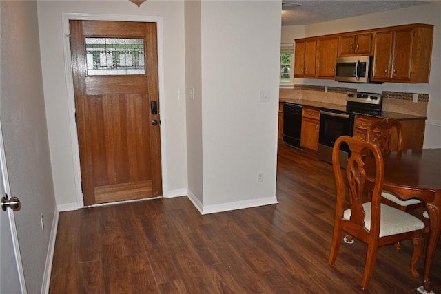 1007 N Bishop St, San Marcos, TX 78666 - kitchen with appliances with stainless steel finishes, dark countertops, brown cabinetry, dark wood finished floors, and baseboards