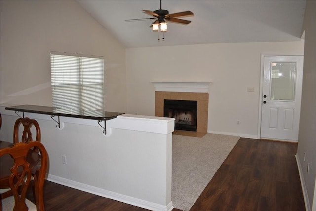 1007 N Bishop St, San Marcos, TX 78666 - living room featuring a ceiling fan, dark wood-type flooring, vaulted ceiling, and a tiled fireplace
