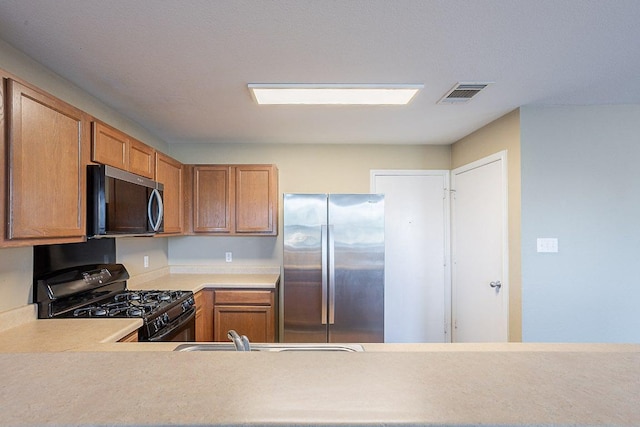 kitchen featuring light countertops, stainless steel appliances, visible vents, and a sink